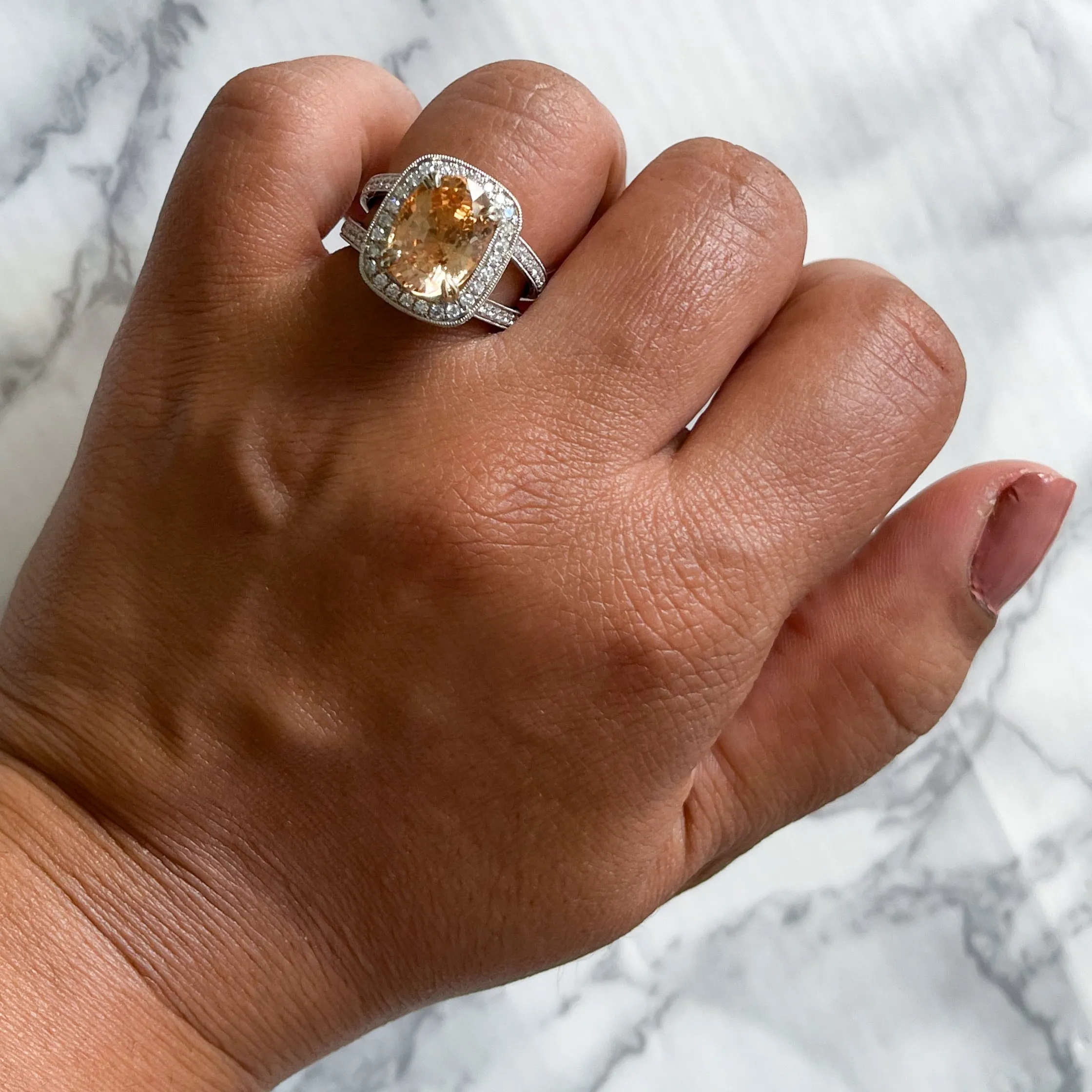 6.58ct Oval Orangey Peach Sapphire with diamond halo in 18K White Gold