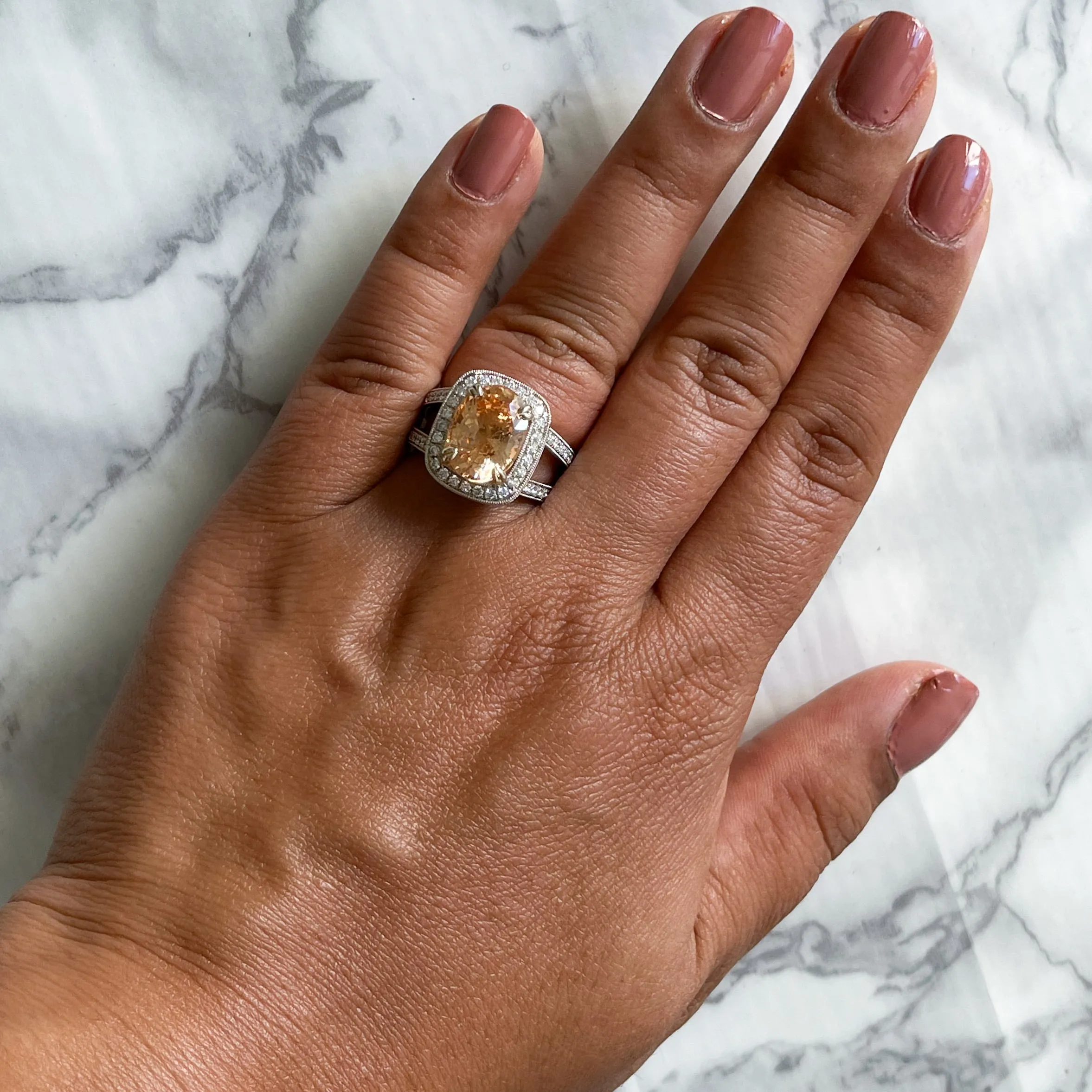 6.58ct Oval Orangey Peach Sapphire with diamond halo in 18K White Gold